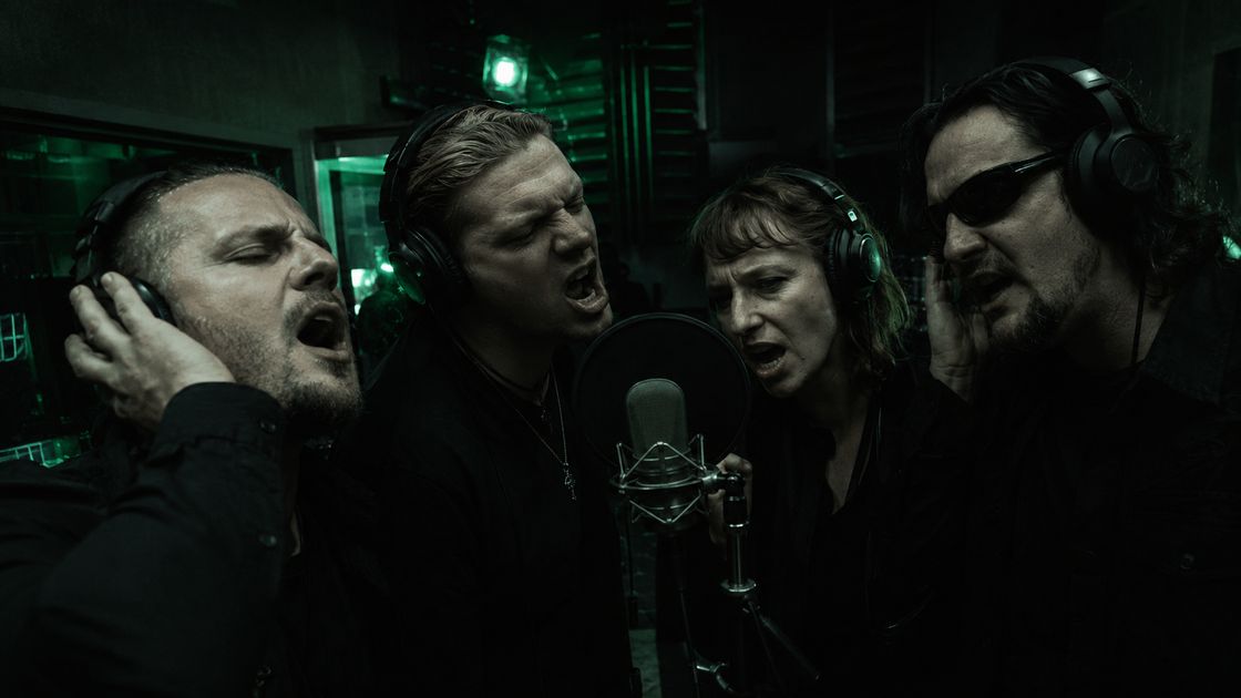 The Dyingpickets Project recording in the studio: four singers in headphones around a condenser microphone, lit only by green light